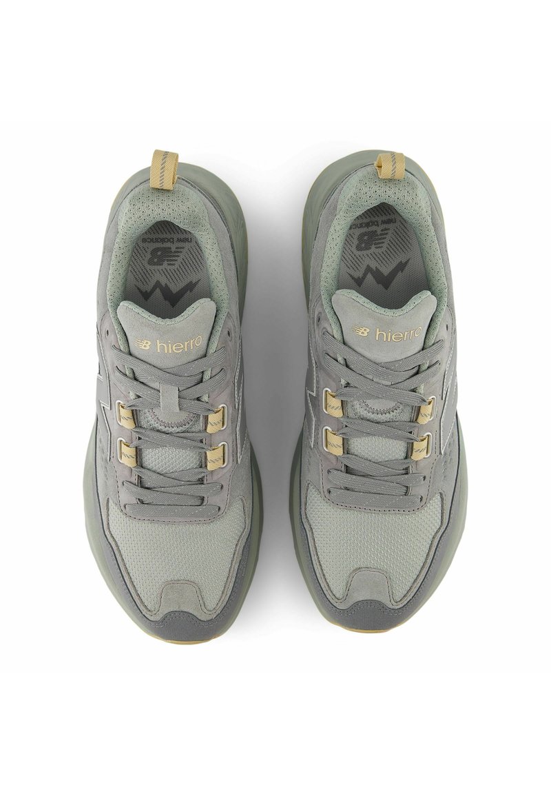 Paire de chaussures de course New Balance Hierro grises et beiges vues de dessus, montrant les lacets, le tissu en mesh et les semelles coussinées.