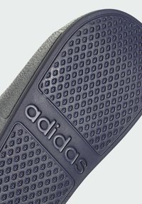 Sole di scarpa Adidas in blu scuro con un motivo testurizzato per la presa e logo visibile, realizzata in materiale gommoso flessibile.