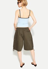 Light blue tank top with black trim, paired with olive green cargo shorts with side pockets, elastic waistband, and drawstrings.