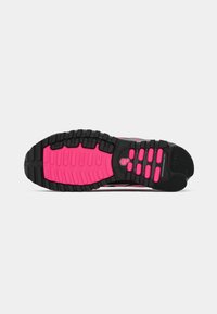 Suela de zapato deportivo negro con acentos de goma rosa, que presenta un relieve texturizado para el agarre y varios tacos para estabilidad y tracción.