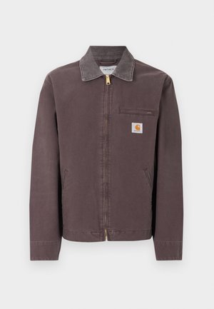 Chaqueta marrón con cremallera y cuello, bolsillo con cremallera en el pecho, dos bolsillos laterales y parche con el logo de Carhartt en el pecho izquierdo.
