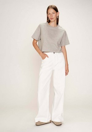 T-shirt gris court à manches courtes associé à un pantalon large blanc. Le pantalon a une fermeture à bouton et des poches latérales. Tissu texturé.