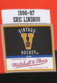 1996-97 Eric Lindros NHL Vintage Hockey Mitchell & Ness con logo di Philadelphia su tessuto rosso e nero.