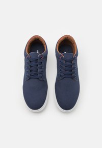 Navy canvas shoes with white rubber soles, featuring six eyelets, brown lining, and contrasting laces. Smooth texture with minimal detailing.