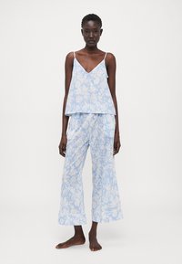 Conjunto de pijama azul claro com padrão, apresentando uma blusa solta com decote em V e calças largas a condizer, ambos com designs florais.