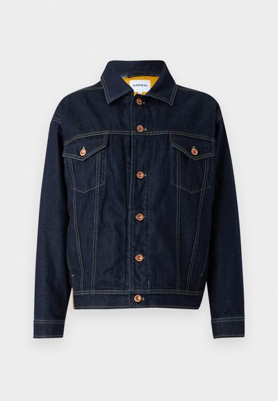 Veste en denim bleu foncé avec quincaillerie cuivrée, deux poches poitrine, une coupe droite et des détails de couture visibles. Design de col classique.