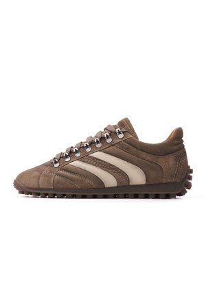 Bruine suède sneaker met beige strepen, metalen oogjes, bruine veters en een gestructureerde rubberen zool, zijaanzicht op een witte achtergrond.