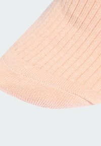 Rebrasta ružičasta čarapa s glatkom teksturom, suženim vrhom i suptilnim varijacijama u debljini pređe, dizajnirana za udobnost i prianjanje.