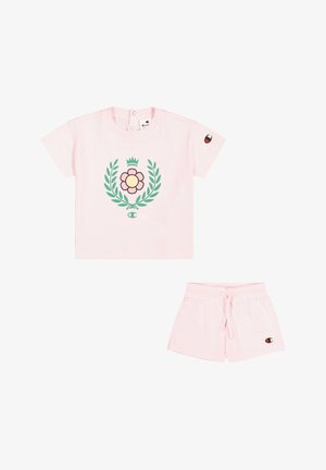 T-shirt rosa in cotone a maniche corte con grafica floreale e foglie verdi, abbinato a pantaloni corti rosa con coulisse. Presenta un'etichetta con logo.