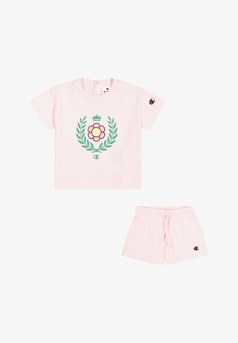Różowa bawełniana koszulka z krótkim rękawem z kwiatowym nadrukiem i zielonymi liśćmi, w komplecie z dopasowanymi różowymi szortami na sznurku. Posiada naszywkę z logo.