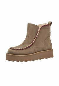 Bruine leren enkelboot met een nepbont voering, contrasterende rode stikdetails en een dikke, gestructureerde zool. Heeft een trekband aan de achterkant.