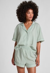 Groene gestreepte pyjama set gemaakt van zachte stof, met een kortekousen overhemd met knopen en shorts met elastische tailleband.