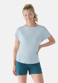 Top corto azzurro chiaro a maniche corte con scollatura rotonda, realizzato in un tessuto morbido. Abbinato a pantaloni corti color teal, con una texture liscia e un design semplice.