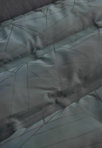 Sötétzöld, fényes felületű, párnázott szövet fekete geometriai mintával. Simaszövet, amely hangsúlyozza a meleget és a szigetelést.
