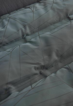 Polstret stof i mørkegrøn med en blank finish, der har et geometrisk mønster i sort. Glat tekstur, der understreger varme og isolering.
