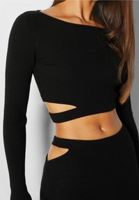 Czarny, prążkowany, dwuczęściowy zestaw z długimi rękawami, z wycięciami w talii i po bokach, dopasowany krój oraz teksturowany materiał.