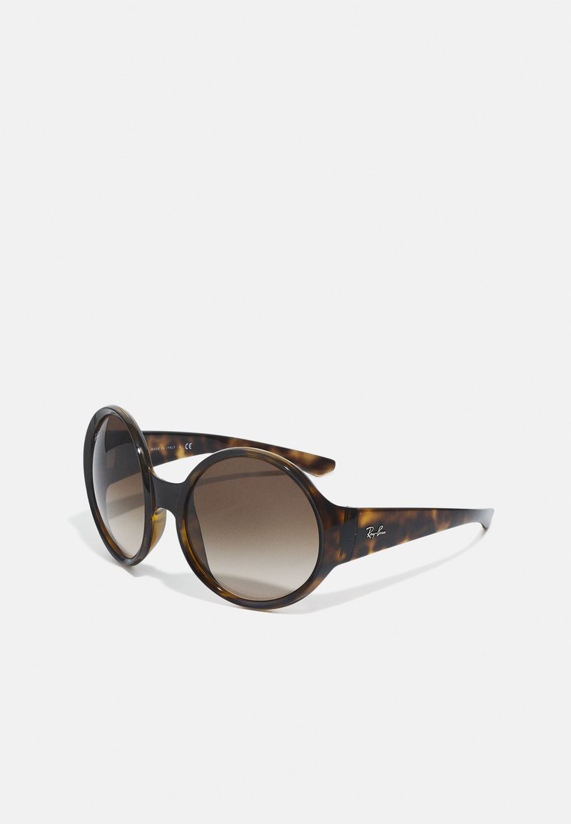 Óculos de sol em padrão tartaruga com lentes ovais grandes e um design elegante. Lentes castanhas degradê e uma marcação subtil na haste.