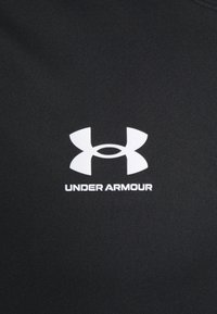 Černé sportovní tričko se bílým logem Under Armour; hladká, lehká tkanina; přiléhavý design určený pro sportovní použití.