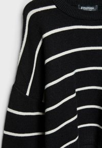 Maglione nero in maglia con strisce orizzontali bianche. Presenta un colletto rotondo a coste e maniche ampie. Texture morbida, design casual.