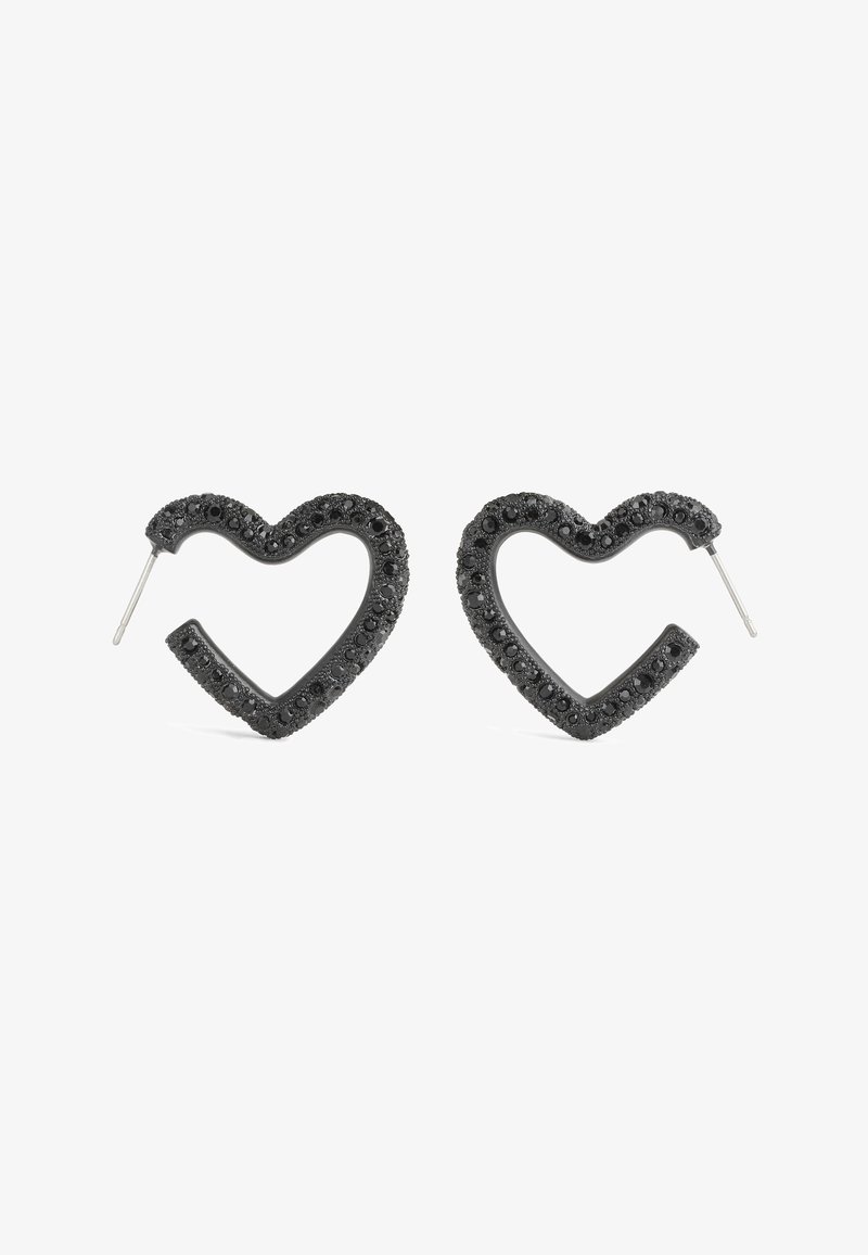 Boucles d’oreilles clous en pierre précieuse noire en forme de cœur avec tiges métalliques sur fond blanc.