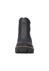 Bottes de cheville imperméables noires avec un dessus lisse, semelle brune contrastante et un zip central pour un accès facile. Semelle en caoutchouc texturée.