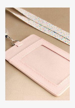 Jasnoróżowy etui na karty z przezroczystym okienkiem na identyfikator, przymocowane do białej smyczy z kolorowym wzorem przypominającym konfetti.