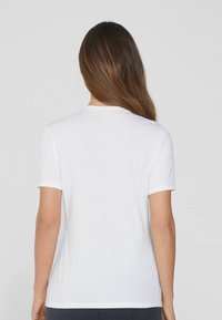 Weiße Kurzarm-T-Shirt, weiches Baumwollmaterial, runder Ausschnitt, schlichte Gestaltung ohne Muster, sichtbare Nähte an den Ärmeln und am Saum.
