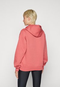 Felpa di un rosa corallo con un cappuccio ampio, polsini e orlo a coste; presenta una vestibilità rilassata e un morbido materiale misto cotone.