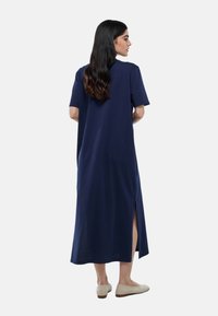 Robe maxi bleu marine en tissu doux, avec des manches courtes, une coupe décontractée et des fentes latérales pour plus de liberté de mouvement.