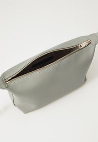 Grå läderpouch med gulddragkedja och platt design, med en mjuk yta och en öppning upptill för enkel åtkomst.