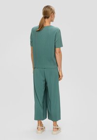 Miętowy zestaw do wypoczynku z prążkowanego materiału, z krótkim rękawem i szerokimi spodniami, w luźnym kroju i miękkiej fakturze. Udekorowany bocznymi rozporkami.