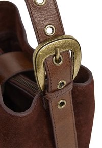 Brown suede bag with leather strap featuring a large brass buckle and metal eyelets, partially open to show an inner zipper.