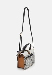 Sac à main à motif python avec un design structuré, doté d'une bandoulière noire, de quincaillerie en or et d'un intérieur beige. Poche zippée à l'avant visible.