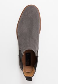 Stivaletto in pelle scamosciata grigio con pannelli laterali elastici, punta rotonda e suola in pelle marrone. Caratterizzato da una linguetta sul retro per facilitarne l'indossamento.
