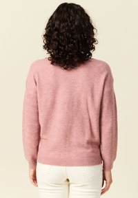 Rosa stickad tröja med ett strukturerat mönster på ärmarna, löst snitt, ribbad nederkant och mjukt, fluffigt material.