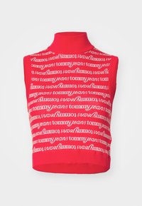 Top court sans manches rouge avec un col haut, présentant un motif répétitif de logo "tommy jeans" blanc sur tout le tissu. Texture côtelée.