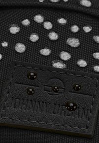 Zaino in tessuto nero con superficie testurizzata, caratterizzato da puntini in rilievo e una patch in pelle nera con la scritta "JOHNNY URBAN" in rilievo.