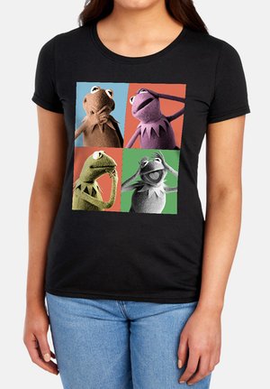 Frau trägt ein schwarzes T-Shirt mit vier bunten Quadraten, die Kermit-Frosch-Puppen in verschiedenen Posen und Hintergründen zeigen.