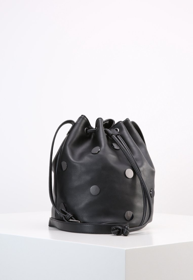 Borsa a secchiello in pelle nera con forma arrotondata, adornata da dettagli metallici a pois. Presenta una chiusura a fune e una tracolla regolabile.