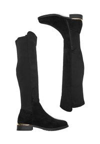 Stivali alti in camoscio nero con cerniera laterale, tacco basso a blocco e accento dorato sul tacco, mostrati da una vista laterale e interna.