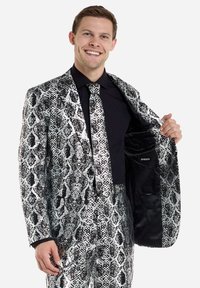Silber- und schwarz gemusterter Anzug mit glänzender Textur, bestehend aus einem Sakko und passender Krawatte, getragen über einem schwarzen Hemd.