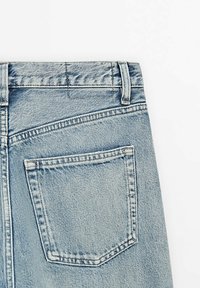 I jeans in denim blu chiaro presentano una tasca posteriore con cuciture visibili, una vita con passanti per la cintura e una texture leggermente sbiadita.