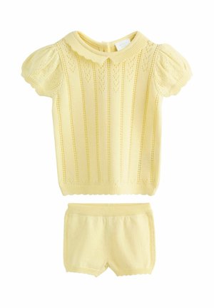 Yellow knitted short-sleeve top with a scalloped collar and heart patterns; paired with matching yellow shorts featuring an elastic waistband.