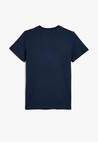 Camiseta azul marino de algodón con mangas cortas, cuello redondo y una superficie texturizada. Diseño simple de un solo color.