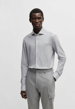 Lichtgrijze langemouwen shirt met een subtiele textuur, knoopsluiting aan de voorkant en een klassieke kraag, gecombineerd met lichtgrijze op maat gemaakte broeken met zakken.