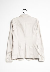 Blazer ajustado en color beige claro con cuello de muesca, abertura trasera y puños de tres botones. Está hecho de una tela suave y cuenta con dos bolsillos laterales.