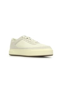 Light beige sneaker featuring a suede and smooth leather upper, round toe, perforated detailing, flat laces, and a thick rubber sole.
