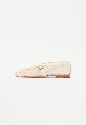 Bailarina tejida color beige con punta afilada, correa de cuero y detalle de hebilla, parte superior texturizada y pequeño tacón marrón.