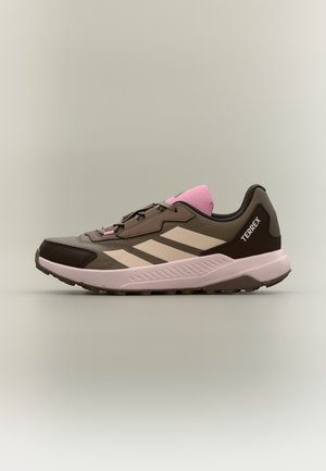 Scarpa da trail Adidas Terrex a basso profilo marrone e rosa con strisce beige e suola texturizzata, vista di lato su sfondo neutro.