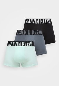 Trys trumpų bokserių poros mėtų žalios, pilkos ir juodos spalvų. Kiekviena turi plačią juodą juostą su „CALVIN KLEIN“ balta raške. Lygi medvilnės medžiaga.
